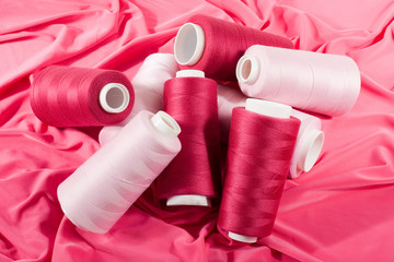 pink and purple bobbins of threads on pink cloth