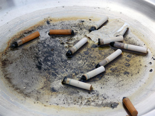 cigarette butts in dirty metal ashtray