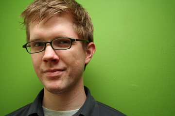 man with glasses against green wall