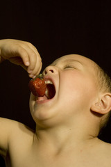little boy with strawberry on black background