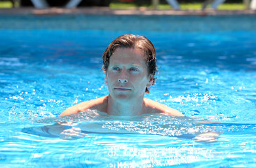 handsome middle aged man swimming in outdoor pool