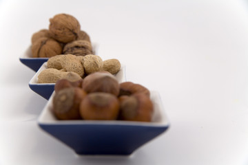 walnuts, hazelnuts and peanuts in three bowls
