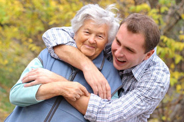 young man hugs elderly woman