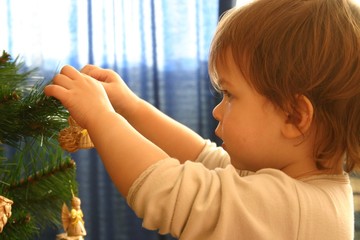 child decorating christmas tree