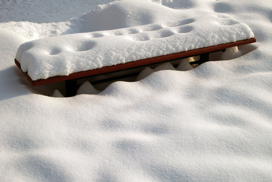 bench under snow by winter