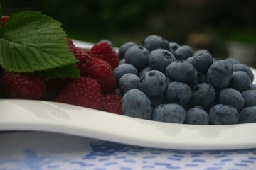 raspberries and blueberries and mint leaf on plate