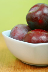 red, purple  plums in a bowl