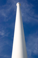 looking up a white flag pole against a blue sky
