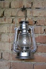 Old vintage oil lamp hanging on a brick wall