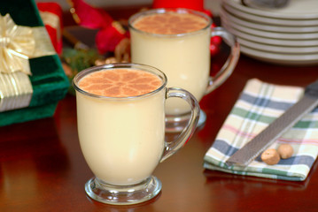 two glasses of rich eggnog in a holiday table setting