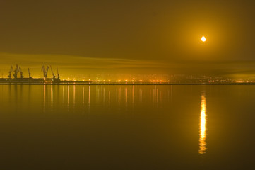 Obraz premium reflections of city and moon in the caspian sea -