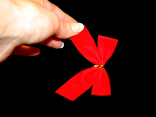 red bow in a hand on the black background