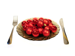 plate with red christmas balls and knite and plug over white