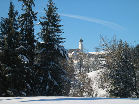 church on hill, behind snowy meadow and trees