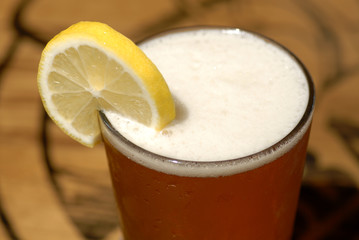 frosty glass of beer with lemon slice