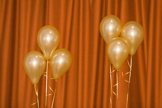 Gold Balloons Against Red Curtain