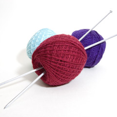 three wool balls and knitting needles