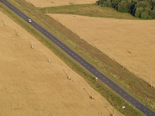 road across field with telegraph pole with automobile.