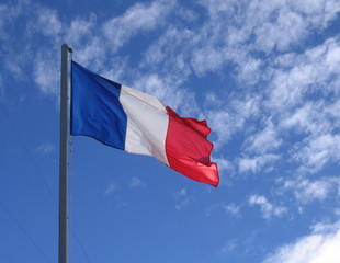 le drapeau tricolore flottant sur un ciel bleu et quelques cumulus
