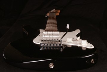 Black, electric guitar with black background, side lit