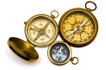 three old style brass compasses