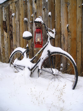 oil lamp and an old bike leaning on a shed in snow