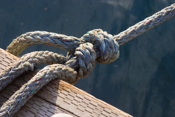 rope tied to a wood boat dock with water visible below