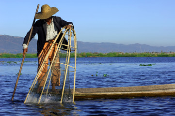 myanmar, inle lake: fishermen on the lake paddling with the help