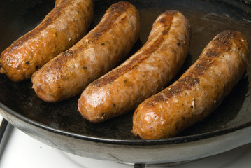 sausages in a black frying pan on gas stove