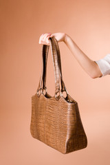 hand holding handbag on the beige background