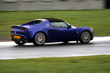 Obraz na płótnie Canvas panoramowanie strzał niebieski samochód sportowy na torze wyścigowym