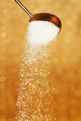 sugar falls from a gold teaspoon
