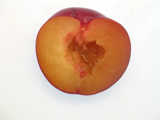 Fototapeta premium eine halbe frische rote Pflaume mit Kern freigestellt auf weißem Hintergrund