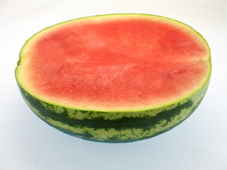 eine halbe frische rote kernlose Wassermelone mit grün-weißer Schale freigestellt auf weißem Hintergrund