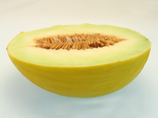 eine halbe frische gelbgrüne Honigmelone freigestellt auf weißem Hintergrund
