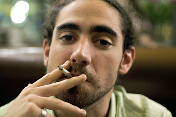 Fototapeta na wymiar jeune homme fumeur dans un lieu public