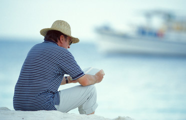 uomo legge sulla spiaggia