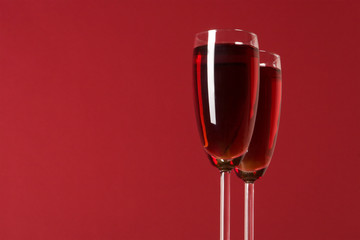 two wineglasses with wine on the red background