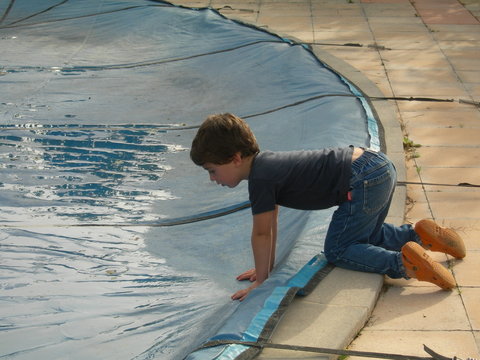 jeune garçon se penchant au dessus d'une piscine