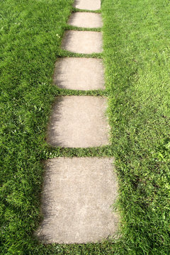 Paving Slab Path Through A Green Grass Garden.