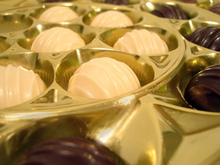 golden box with white and chocolat sweets close-up