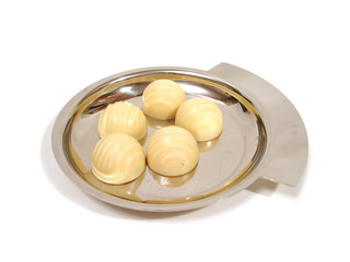 light chocolates on a silver plate over white background
