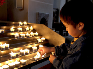 kleiner Junge zündet eine Kerze in der Kirche an