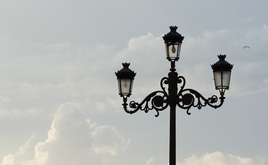 Fototapeta na wymiar streetlamp against blue sky with clouds