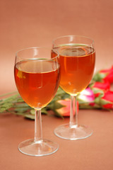 two wine glasses and flowers at the background