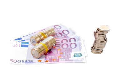 stack of coins over a euro bills