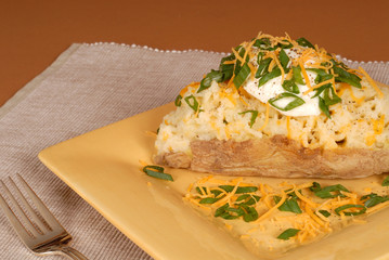 a twice baked potato with scallions, cheese and sour cream