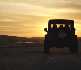 vehicle in the wilderness at sunset - obrazy, fototapety, plakaty