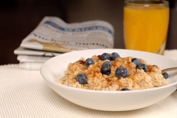 bowl of oatmeal with brown sugar, blueberries, orange juice