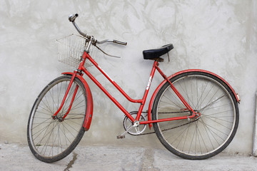 old red bicycle leaning against a wall